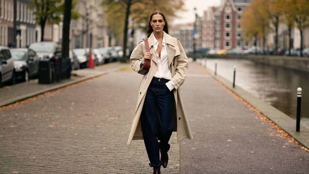 Herfst outfit dames met beige trenchcoat, witte blouse en jeans op straat