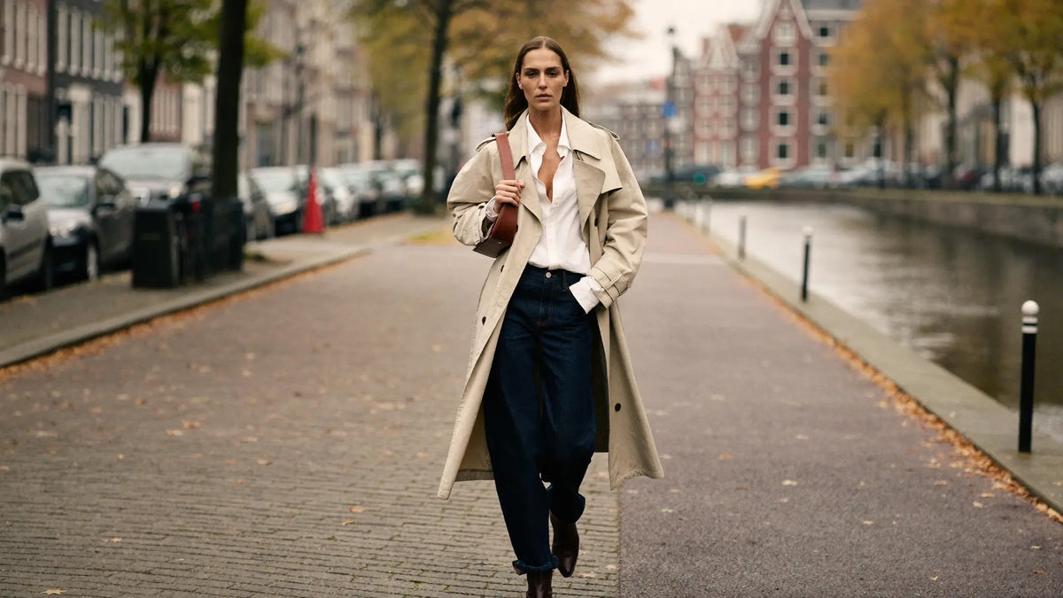 Herfst outfit dames met beige trenchcoat, witte blouse en jeans op straat
