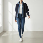 Woman wearing a navy knit cardigan with a denim collar, white tee, dark jeans, and white sneakers.