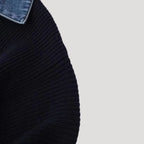 Close-up of a navy blue knitted cardigan with a denim collar and ribbed texture.
