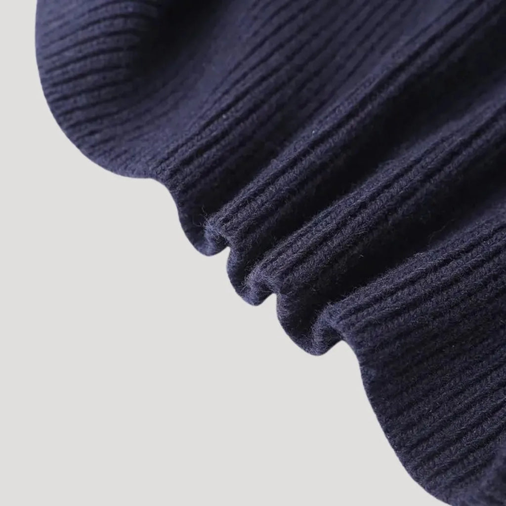Close-up of a navy blue ribbed knit cardigan with a unique denim collar and button closure.