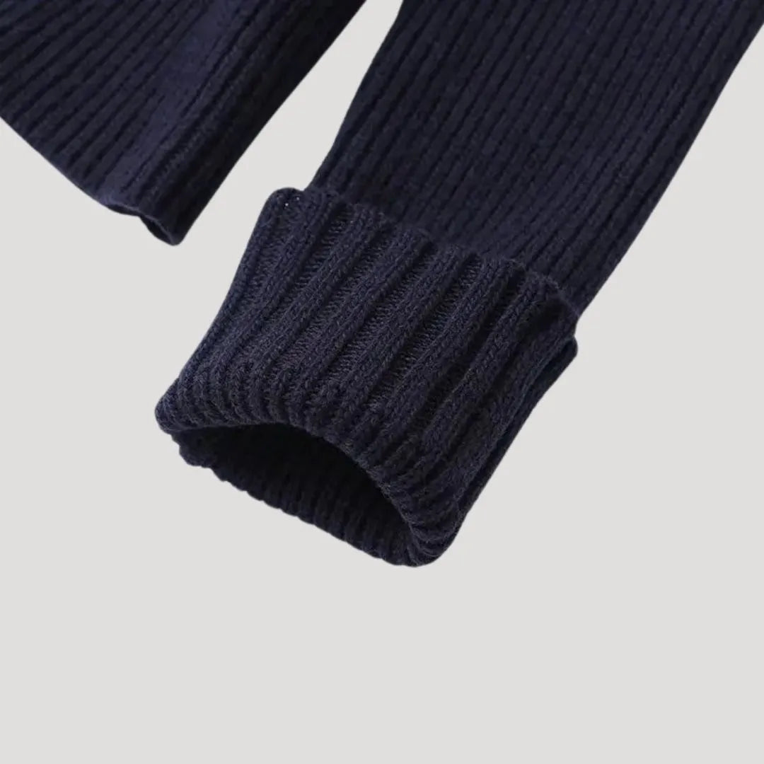 Close-up of a navy blue ribbed knit cardigan sleeve with a folded cuff.