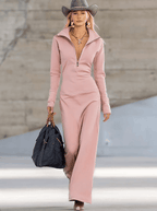 Woman in a light pink knit maxi dress with quarter-zip, holding a black bag, wearing a cowboy hat.
