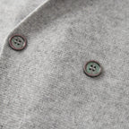 Grijze double-breasted blazer van 100% gekamde cashmere met donkere knoopdetails.