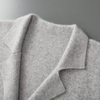 Grijze damesblazer van 100% gekamde cashmere met klassieke reverskraag en verfijnde gebreide textuur.