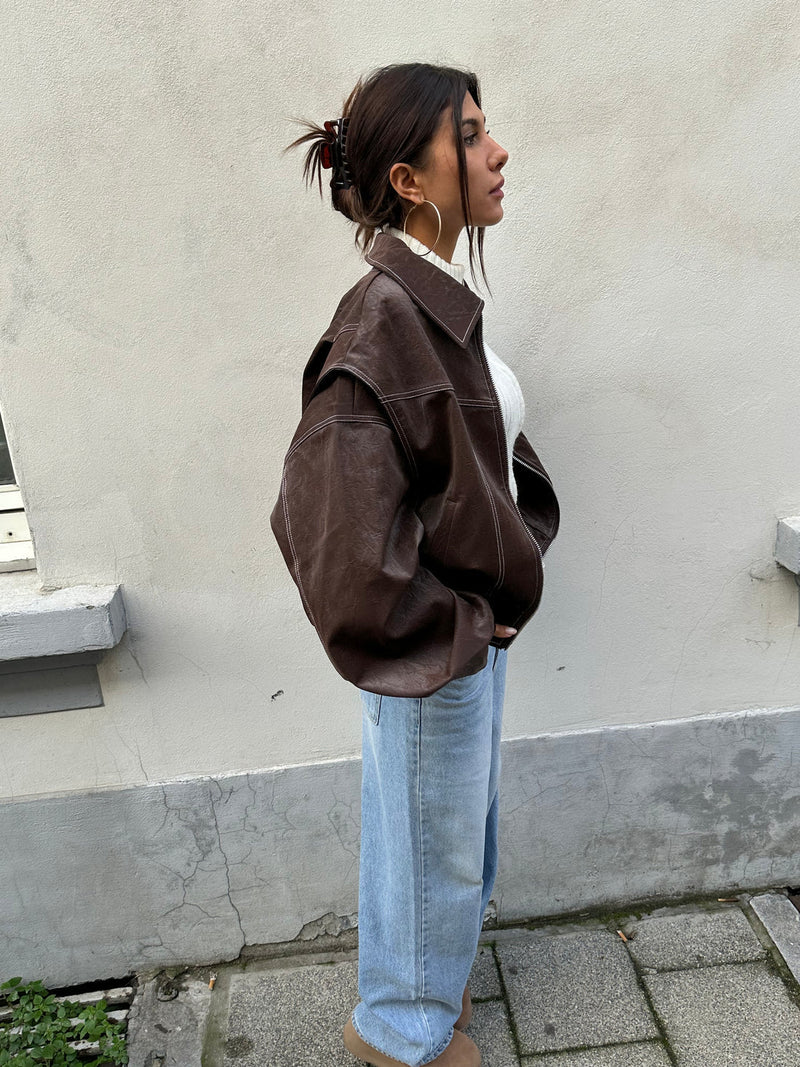 Bruin oversized bomberjack van polyester met rits en witte stiksels, gedragen door een vrouw.