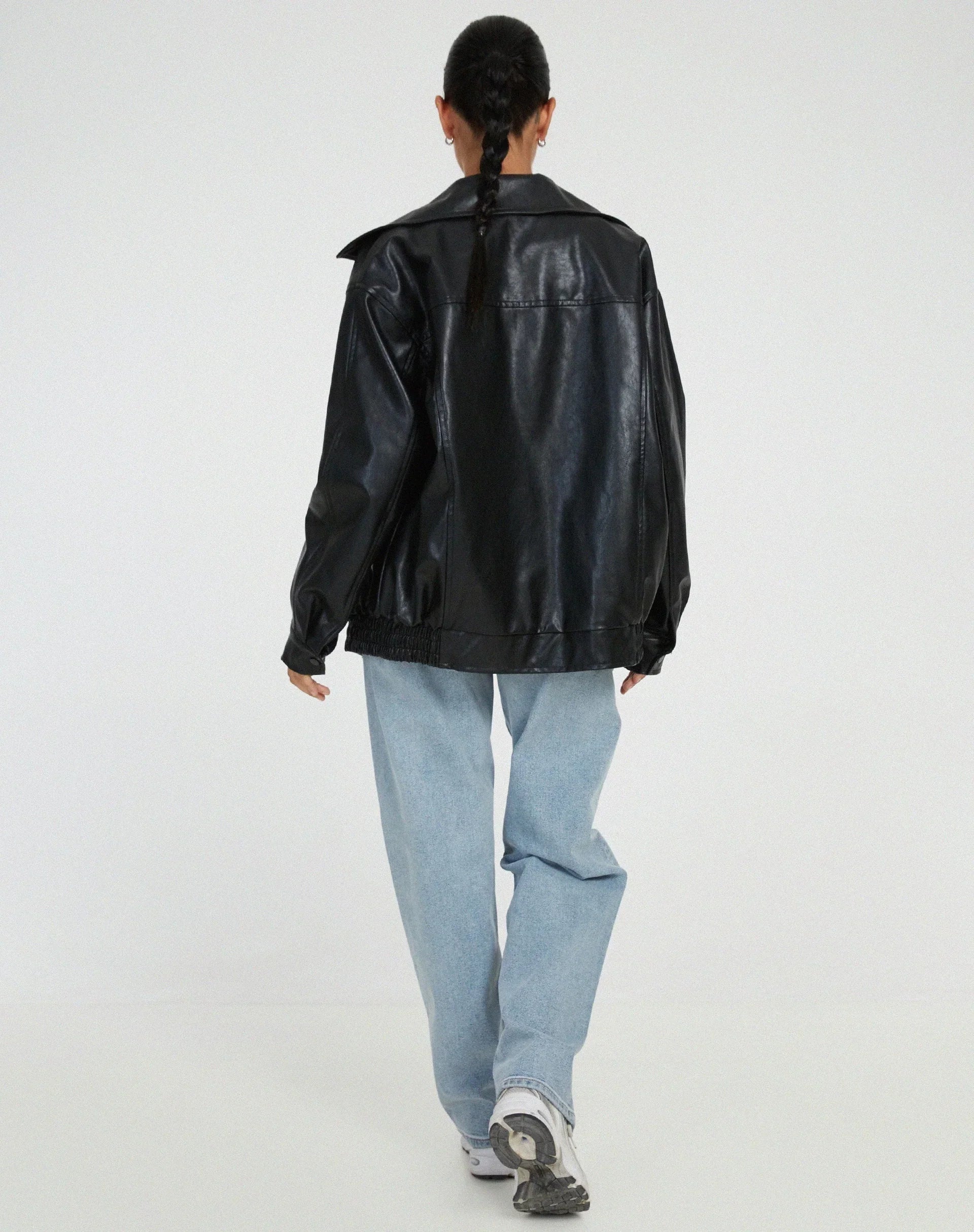 Blouson femme noir en similicuir, style motard, avec fermeture éclair et deux poches latérales.